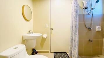 A bathroom with a toilet, sink, shower, and a door.