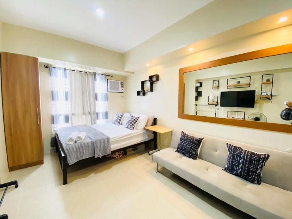 Un dormitorio con cama, sofá, armario, espejo y televisión.