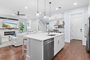 A modern kitchen with a central island, white cabinetry, and a built-in dishwasher. - Maison de Paix | Luxury NatureWalk Home | Golf Cart + 6 Bikes | Sleeps 11 (Santa Rosa Beach)
