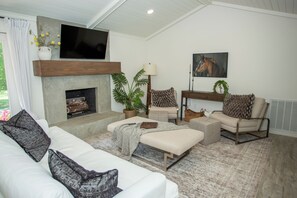 A living room with a fireplace, a television, and a horse painting on the wall. - The Carolhaus A Country Retreat Close to Murfreesboro (Murfreesboro)