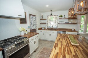 A modern kitchen with white cabinets, a wooden countertop, a gas stove, and a built-in dishwasher. - The Carolhaus A Country Retreat Close to Murfreesboro (Murfreesboro)