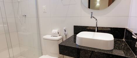 A modern bathroom with a white toilet, a sink with a black countertop, and a shower area.