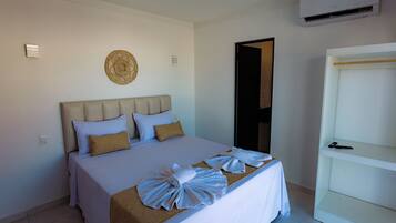Habitación de hotel con cama, mesita de noche, armario y aire acondicionado de pared.