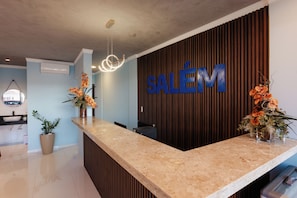 A reception desk with a 'SALÉM' sign, a modern light fixture, and potted plants.