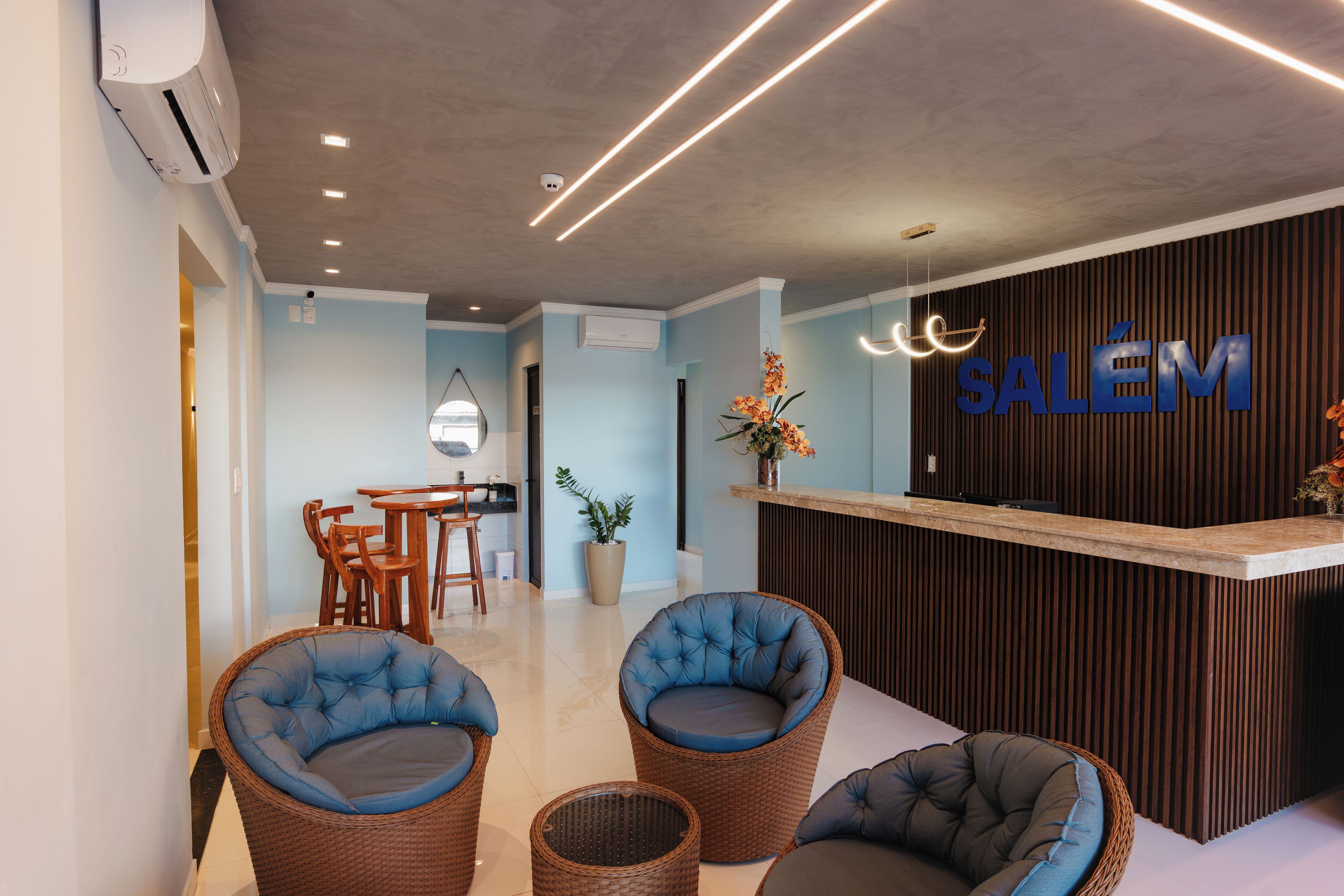 A reception area with a 'SALÉM' sign, wicker chairs, a small table, and a potted plant.