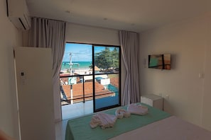 Une chambre d’hôtel avec un lit, une télévision et une vue sur une plage et des immeubles.