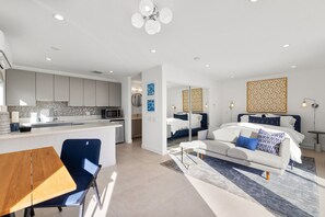 Eine moderne Wohnung mit Küche, Essbereich und einem Schlafzimmer mit großem Bett und Schlafsofa.