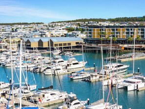 A marina with numerous boats docked, a waterfront restaurant, and residential buildings in the background. - Salty Air Coastal Cottage, Pet Friendly (Lake Illawarra)