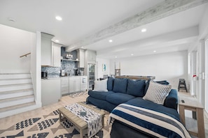 Un espacio habitable moderno con sofá, mesa de centro y zona de cocina.