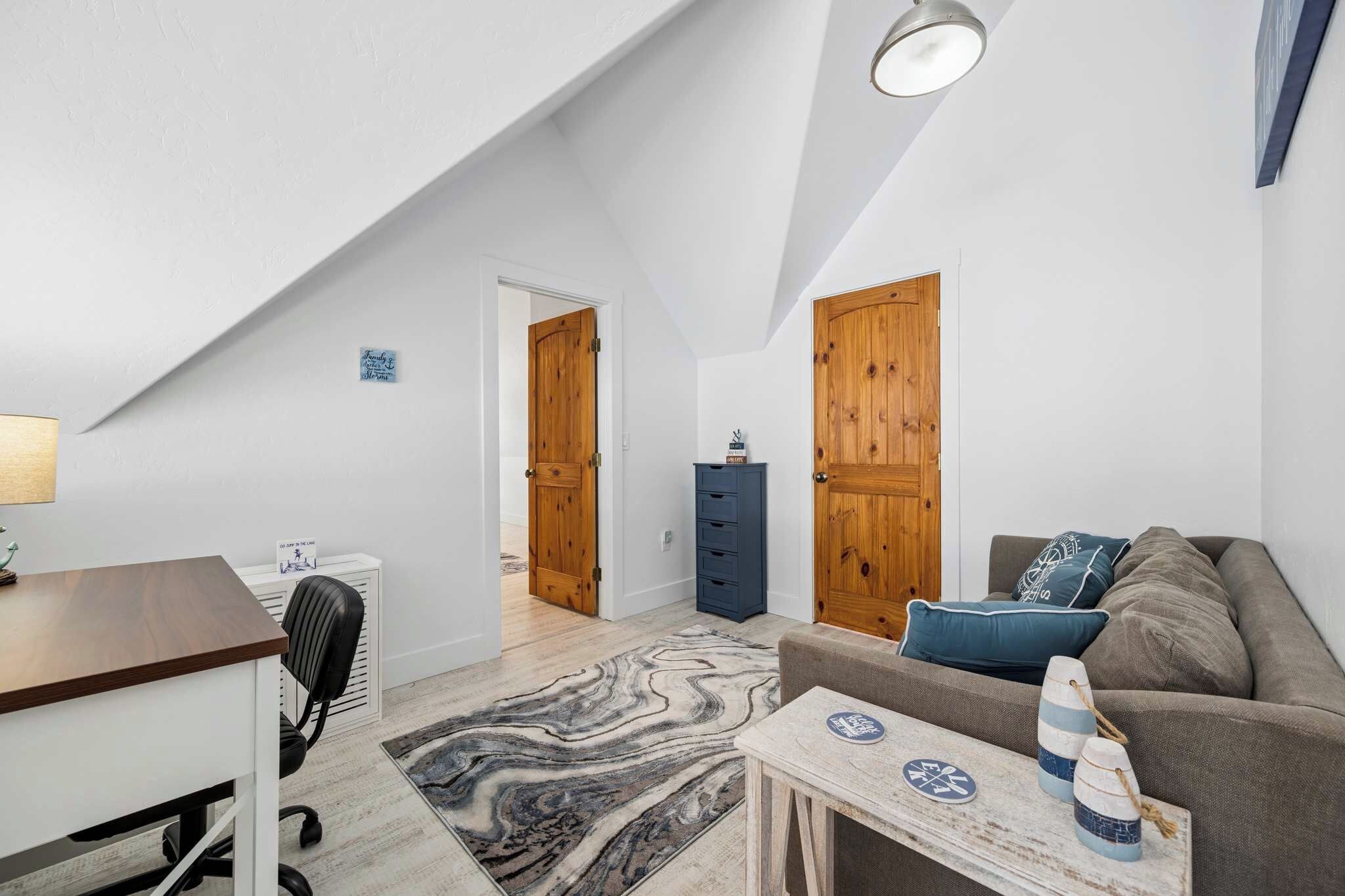 Une pièce de style loft comprenant un bureau, une chaise, un canapé et une petite table agrémentée d'objets décoratifs.
