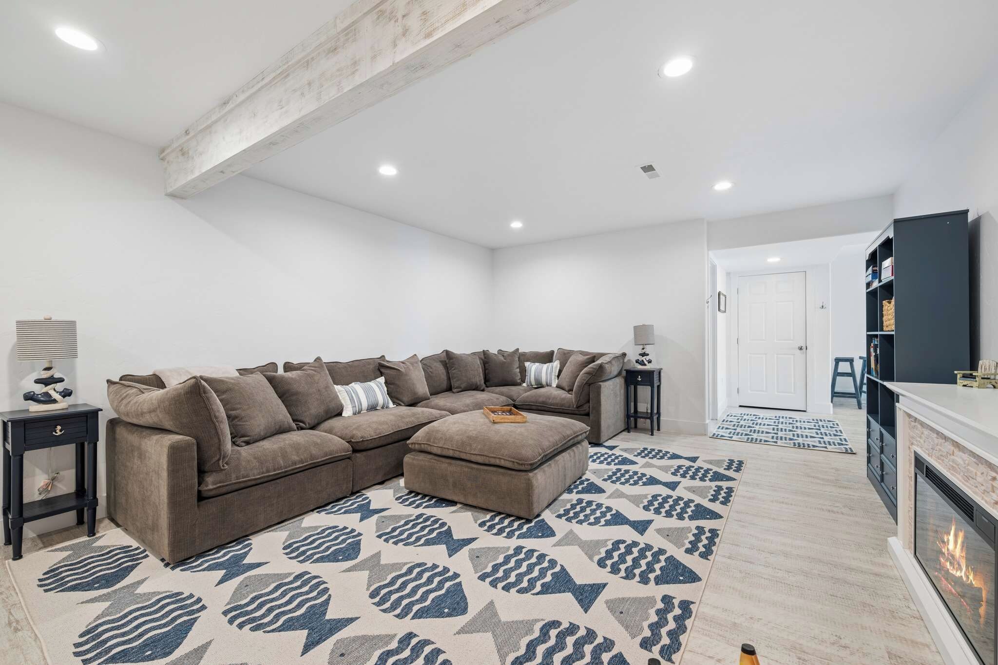 A modern living room with a sectional sofa, a fireplace, and a patterned rug.