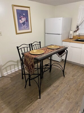 A dining table with chairs, a refrigerator, and a sink in a kitchen. - Cozy and Comfy "Away from Home" (Pine Bluff)