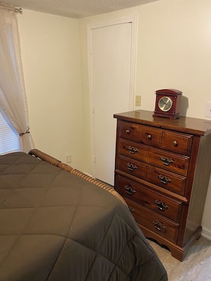 A bedroom with a bed, a dresser, and a wall clock. - Cozy and Comfy "Away from Home" (Pine Bluff)