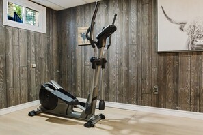 Ein Heim-Fitnessraum mit Crosstrainer, Holzwänden und einem gerahmten Bild eines Elches.