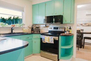 A kitchen with teal cabinets, a stainless steel stove, and a microwave. - LUX Heaven Sydney | 5BR, Pool Table, BBQ & Fireplace (Sydney)