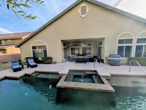 Ein Wohnhaus mit Swimmingpool, Sitzgelegenheit im Freien und Grill.