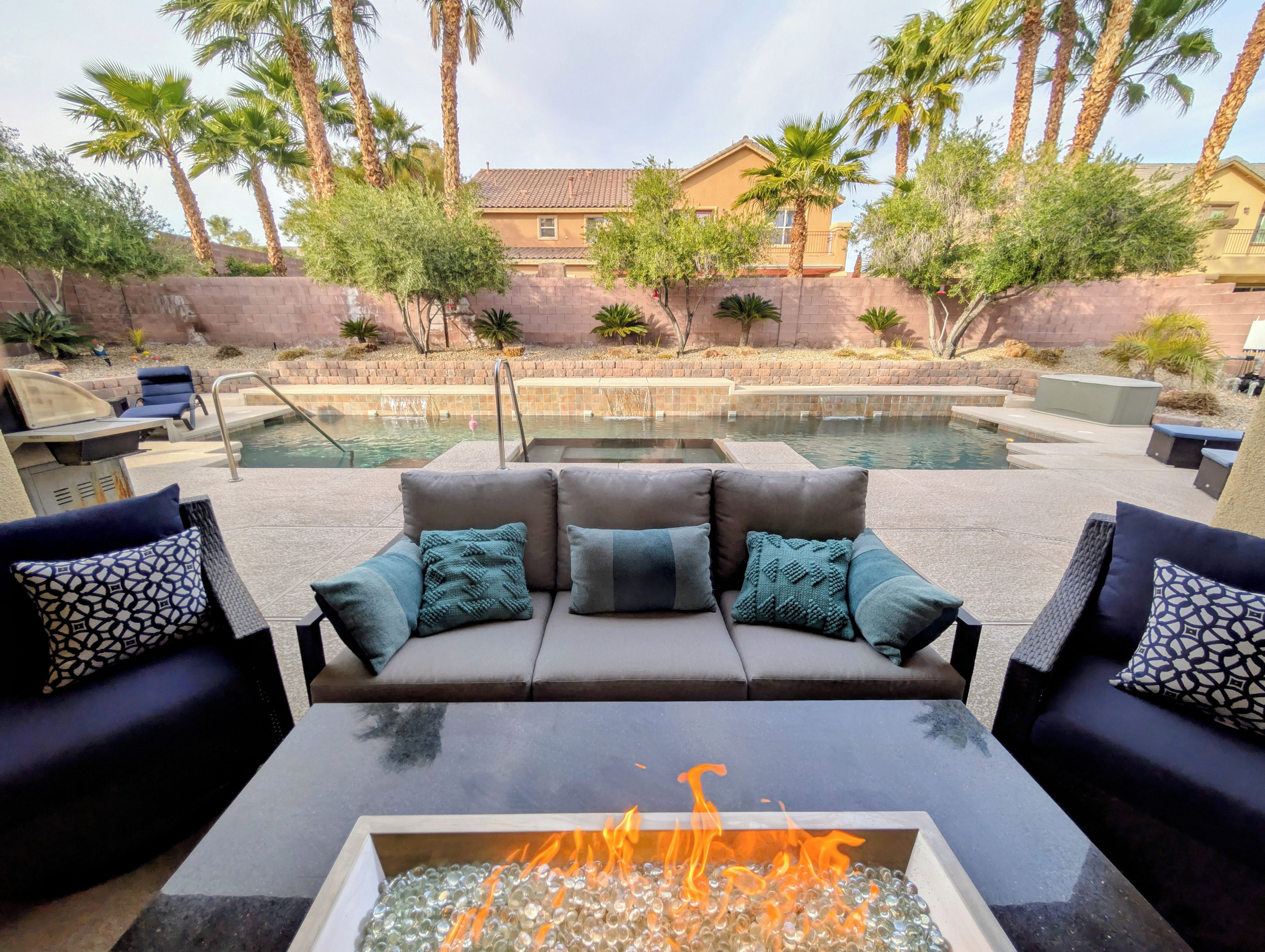 A poolside area with a sofa and fire pit.
