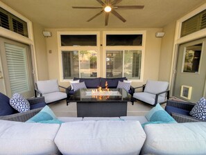 Eine Terrasse im Freien mit einem Tisch aus Glas, einem Feuerkorb und einer Sitzgruppe.