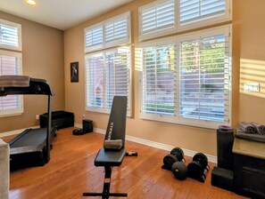 A home gym with a treadmill, bench, and dumbbells. - Poolside Retreat in North Summerlin (Las Vegas)