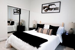 A modern bedroom with a large bed, bedside tables with lamps, a mirror, and abstract wall art. - Immerse Yourself in Sedona’s Natural Beauty. (Sedona)