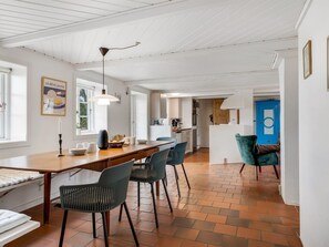 Een moderne keuken met een houten tafel, stoelen en een hangende lamp.