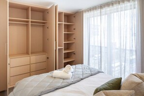 A bedroom with a bed, a large wardrobe, and a window with curtains. - Book 1 get 2, Central Apartments - Walk to Stadium (Christchurch)