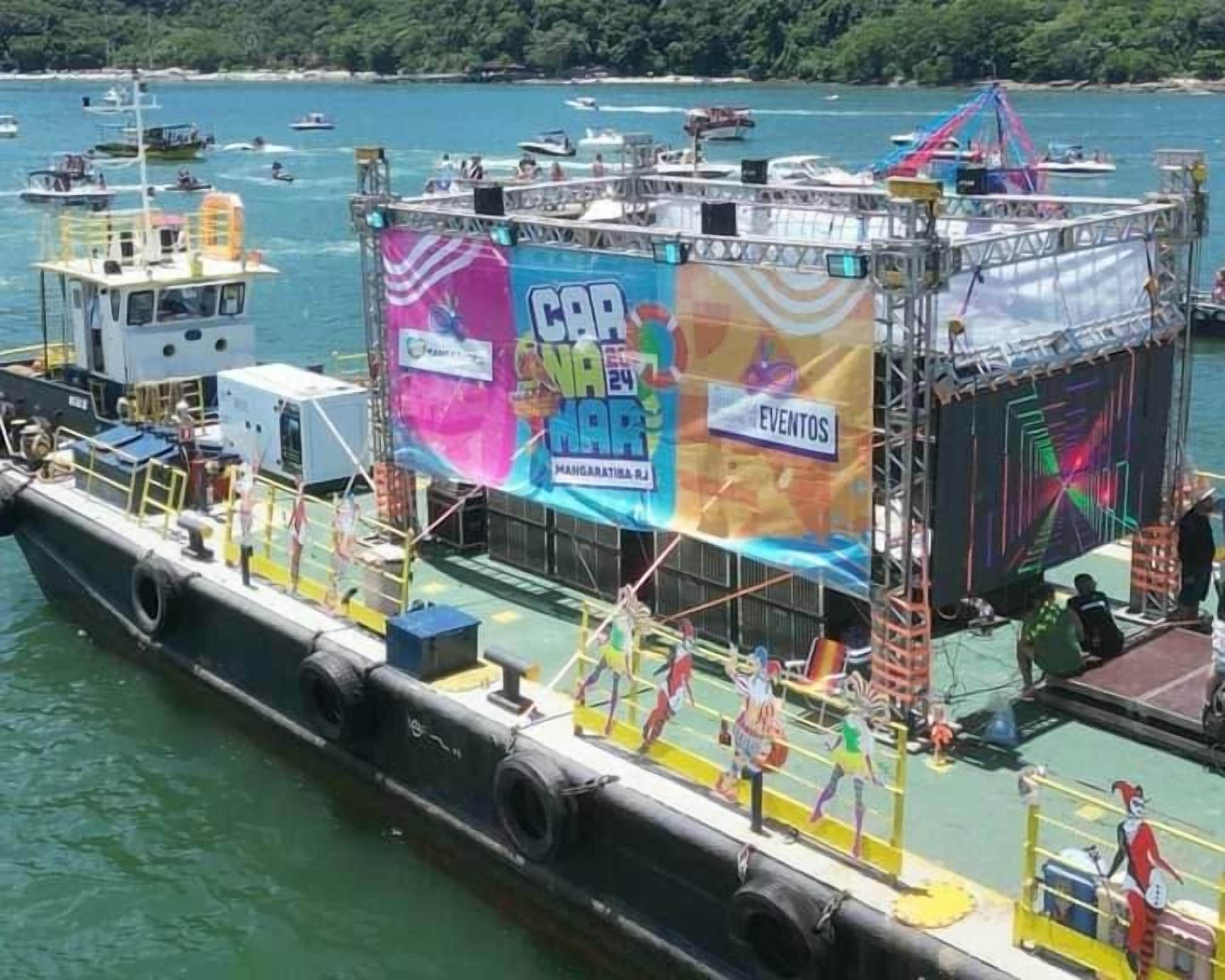 Un bateau sur lequel est installé un grand écran diffusant une publicité pour un événement.
