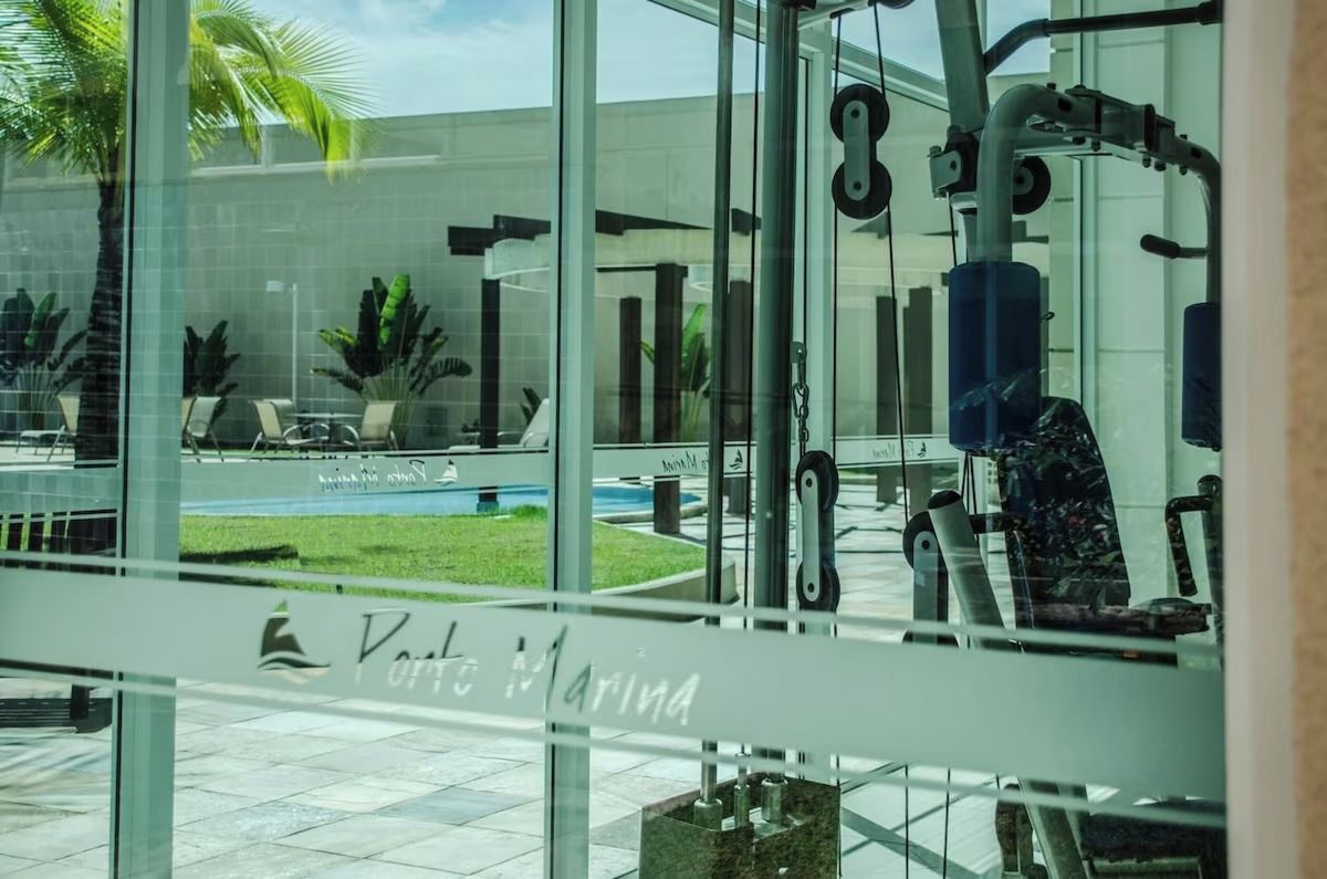 Un gimnasio con equipamiento de ejercicio, una pared de vidrio y un letrero que dice 'Porto Marina'.