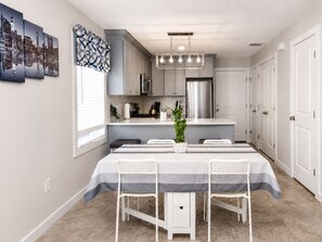 A modern kitchen with a central island, stainless steel appliances, and a dining area with a striped tablecloth. - Stylish 3BR Retreat w/ Backyard Near MetLife, American Dream & NYC (Belleville)