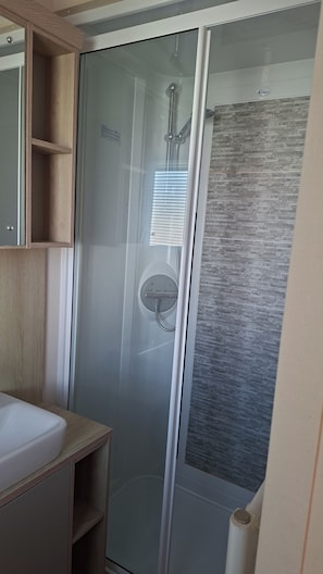 A modern bathroom with a glass-enclosed shower, a wooden vanity, and a textured wall. - 30C Kingfisher Hottub Lodge (Tattershall)