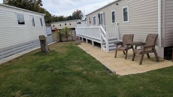 Una hilera de casas móviles con césped y una terraza de madera.