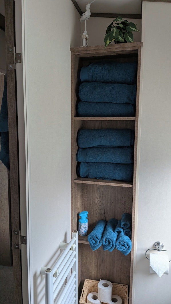 A wooden shelf with folded towels and a bottle of hand sanitizer. - Caravan sleeps 6 with access to indoor pool (Dunbar)
