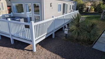 Ein Wohnmobil mit einer Terrasse, einer kleinen Veranda und einer Auffahrt mit Kies.