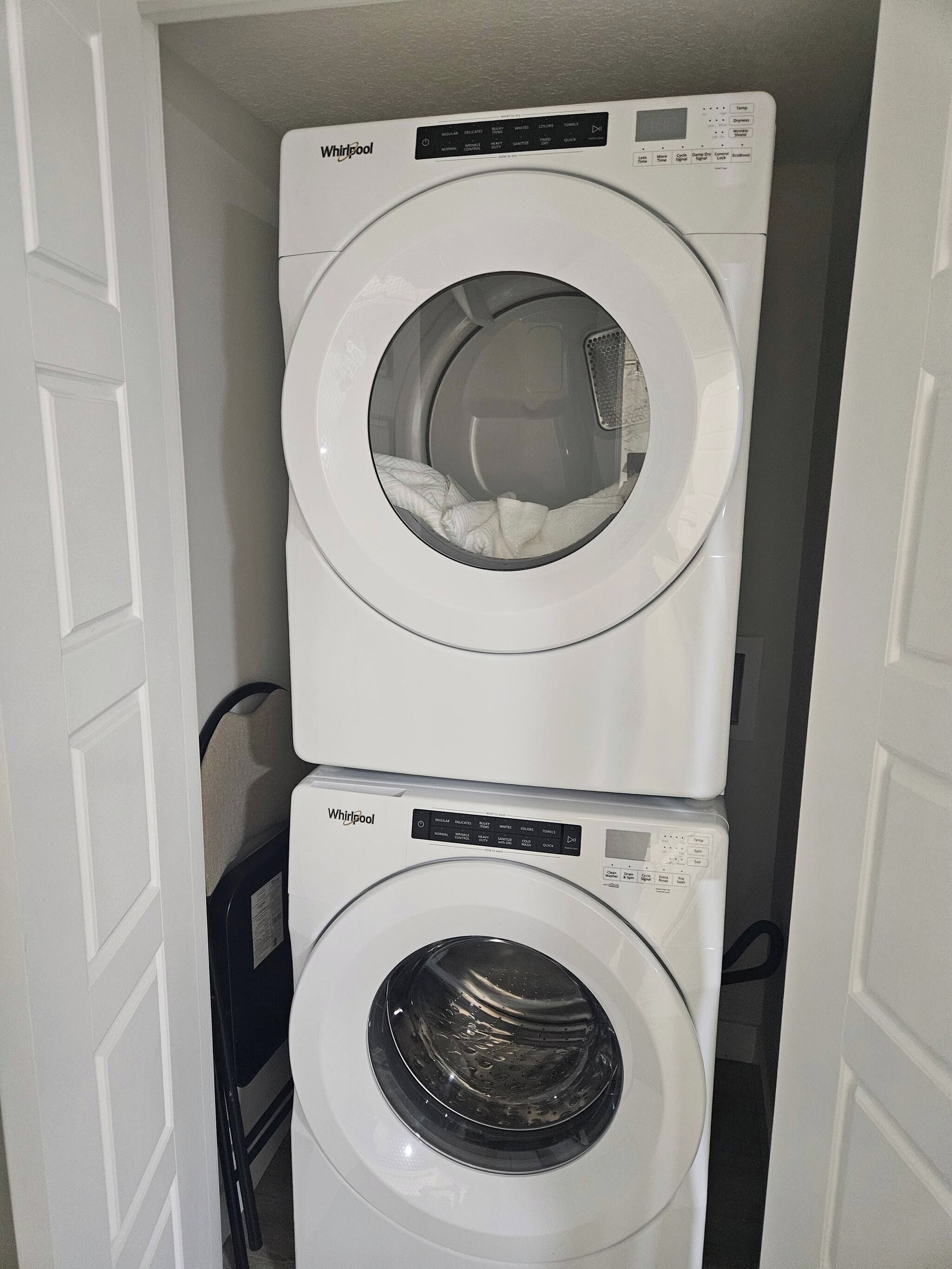 Dos lavadoras de carga frontal Whirlpool apiladas en un cuarto de lavado.