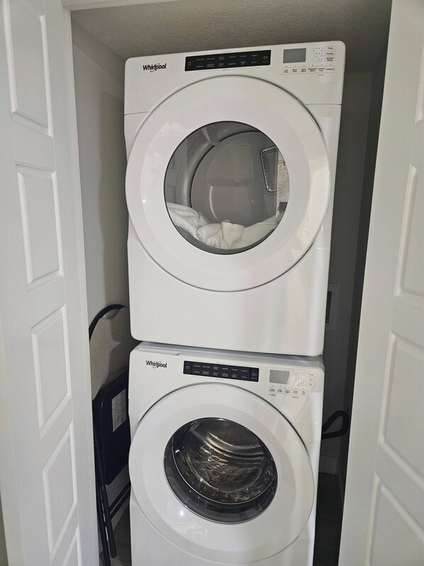Dos lavadoras de carga frontal Whirlpool apiladas en un cuarto de lavado.