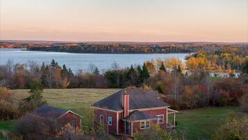 A house with a view of a lake and autumn foliage.