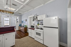 Une cuisine avec des meubles blancs, une cuisinière, un réfrigérateur et un plan de travail en bois.