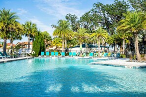 Ein Swimmingpool mit klarem, blauem Wasser, umgeben von Palmen und Liegestühlen.