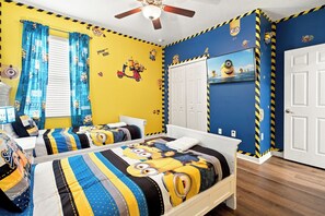 Ein Schlafzimmer mit zwei Betten, einem Deckenventilator und Minion-Dekoration.