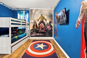 Ett barnrum med en våningssäng, affischer med superhjältar och en matta med Captain America-tema.
