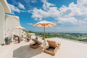 A rooftop terrace with lounge chairs, umbrellas, and potted plants. - Villa Veluna Uluwatu (Uluwatu)