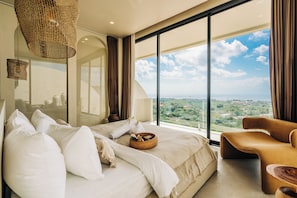 A bedroom with a large bed, a sitting area, and a view of the landscape. - Villa Veluna Uluwatu (Uluwatu)