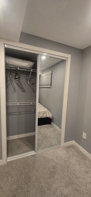 Una habitación con armario que tiene espacio para colgar ropa y una cama con colcha estampada.