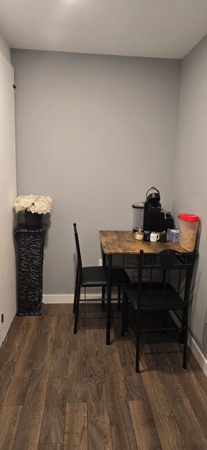 Un comedor con una mesa de madera, sillas negras, un bote de basura negro y una planta en maceta.