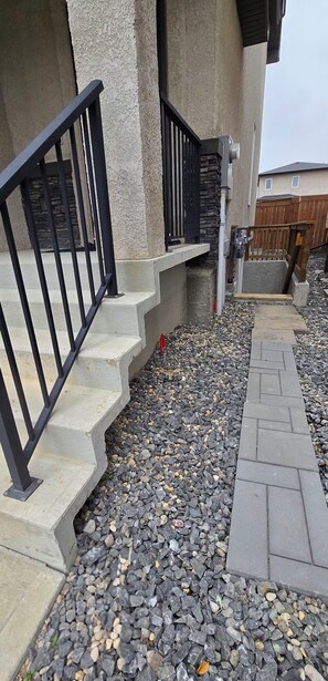 Una escalera de hormigón con barandillas negras que lleva a una terraza de madera.