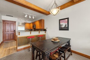 Eine moderne Küche mit Holzschränken, einem Edelstahlkühlschrank, einer Mikrowelle und einer Bar mit Hockern.