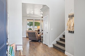 A hallway with a wooden floor, a door leading to a living room, and a staircase with a textured wall. - 4BR, 4BA villa in Sienna Hills with pool, hot tub & resort amenities. (Washington)