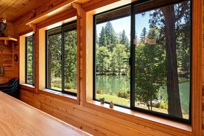 A cabin with large windows overlooking a lake and forest.