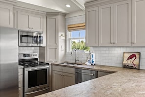 A kitchen with stainless steel appliances, a granite countertop, and a view of the outdoors. - Casa Flamingo- Canal Front | Great for Families (Galveston)