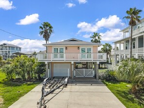 A two-story house with a garage, a balcony, and a driveway. - Casa Flamingo- Canal Front | Great for Families (Galveston)